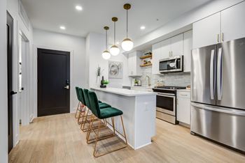a kitchen with stainless steel appliances and an island with green chairs at Rialto, Washington